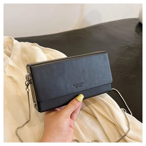 Detail of a black square crossbody bag with silver chain strap and brand lettering