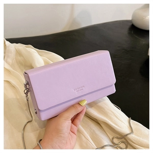 Detailed shot of lavender square leather bag with silver chain strap and embossed text