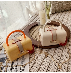 Detail of trendy acrylic jelly box bags in cream and yellow with contrasting handles