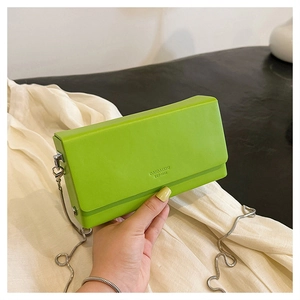 Detail of green square chain bag featuring embossed lettering and silver metal link