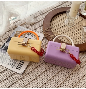 Detailed view of yellow and purple hardshell jelly bags with gold chain and red link deco