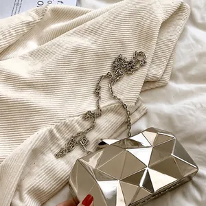 Detail of silver acrylic clutch bag with geometric diamond cut surface and metal chain