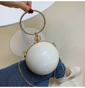 Detail of white spherical clutch bag with a rhinestone-studded circular metal handle