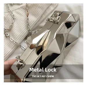 Detail of artistic hardware clasp on silver geometric acrylic cube evening clutch bag