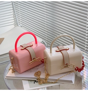 Detail of pink and cream acrylic jelly bags with golden chain straps on a table