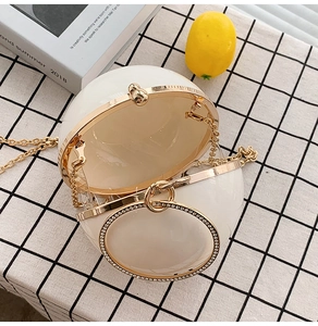 Detailed view of white spherical clutch featuring a crystal-embellished metal handle