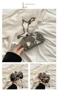 Detail of black acrylic clutch with geometric cube facets and metal chain strap