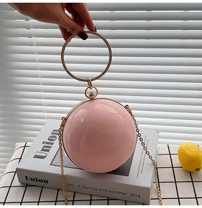 Close-up of pink spherical evening bag with rhinestone-studded metal ring handle