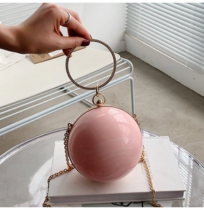 Detail of a spherical pink evening bag with rhinestone-studded gold round handle