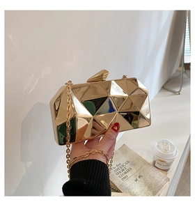Detail of a geometric gold mirrored clutch bag with metallic chain and triangular facets