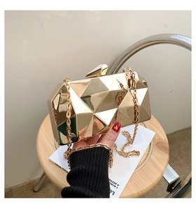 Detail of golden geometric evening clutch bag with mirrored finish and metal chain