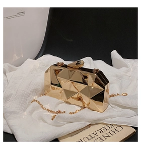 Macro view of golden geometric clutch bag with multi-faceted mirror finish and metal chain