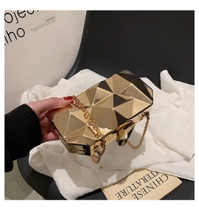 Close-up of golden geometric evening clutch bag with faceted surface and chain strap