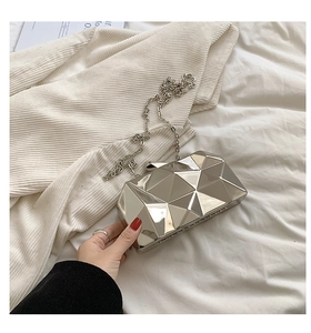 Detail of silver geometric acrylic clutch bag with metallic facets and chain strap