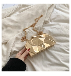 Detail view of gold geometric faceted clutch bag with a metallic finish and thin chain