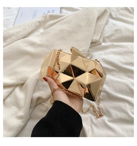 Close-up of golden geometric cube evening clutch bag with metallic mirror finish and chain