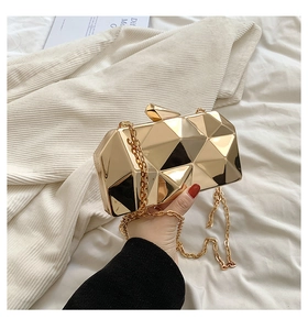 Detailed view of golden geometric clutch bag with mirror finish and metal chain