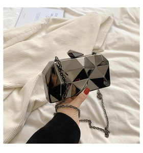 Detailed close-up of a black acrylic cube clutch with geometric facets and metal chain