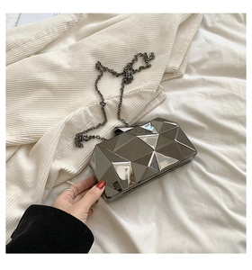 Detail view of a gunmetal acrylic clutch bag with geometric 3D water cube patterns