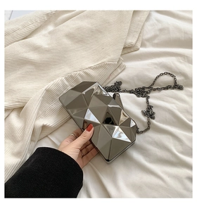 Macro view of geometric faceted silver mirror clutch with sleek metallic chain strap