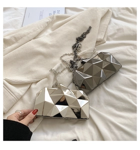 Detail of geometric acrylic evening clutch with mirror finish and metallic chain strap