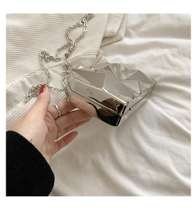 Detailed close-up of a silver geometric cube evening clutch bag with a metallic chain strap
