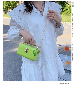 Neon green marble acrylic box bag with golden chain strap shown in a street lifestyle setting