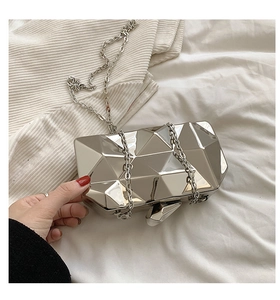 Detail of silver geometric evening bag showing mirror finish and chain strap