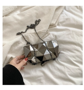 Detail of geometric faceted acrylic evening clutch with metal chain strap and mirror finish