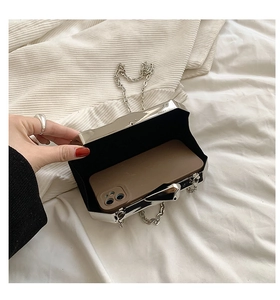 Silver metallic hard shell clutch showing internal capacity with a smartphone