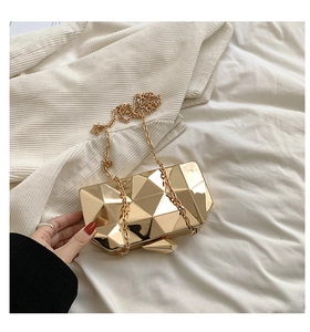 Macro detail of gold geometric cube evening clutch bag with metallic mirror finish
