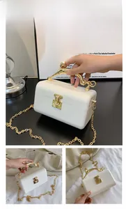 Detail of cream acrylic clutch bag with gold deer handle and metal chain strap