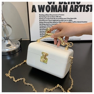 Detailed view of a white acrylic evening bag with a gold horse-shaped metal handle and chain