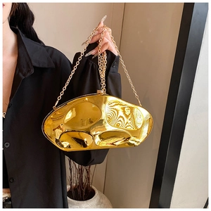 Golden acrylic mirror-effect crossbody bag with wavy texture on black shirt