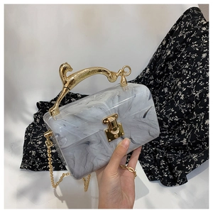 Detail of marble acrylic evening bag with gold leopard handle and chain strap