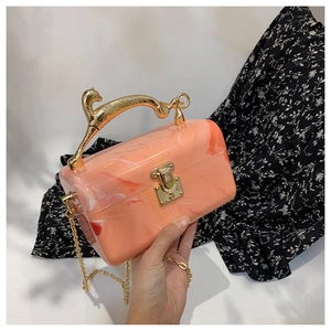 Detail of candy-colored acrylic box bag with golden leopard handle and marble texture