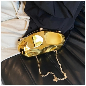 Detail of a golden irregular pebble-shaped acrylic evening bag with a metallic finish