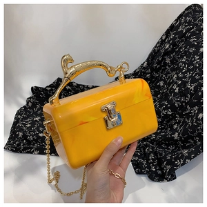 Detail of yellow marble acrylic clutch bag with elegant golden leopard metal handle