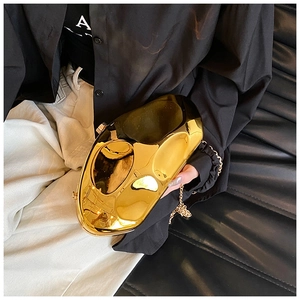 Close-up of a gold sculptural clutch bag with metallic mirror finish and chain strap