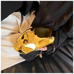 Detail of a polished gold pebble-shaped acrylic clutch bag with a metallic chain strap