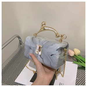 Detail of marble pattern acrylic evening clutch bag with gold deer-shaped metal handle