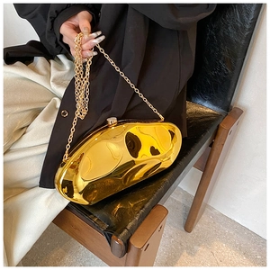 Golden irregular clutch bag with mirror finish and metal chain held by a model