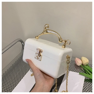 Detail of white acrylic clutch bag featuring a gold horse-shaped handle and chain strap