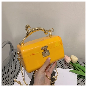 Macro shot of yellow marble acrylic bag with a golden leopard handle and metal chain