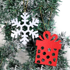 Detail of felt snowflake and red gift box ornaments hanging on a Christmas tree
