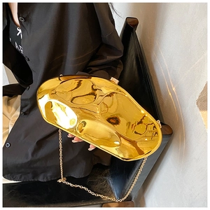 Close-up of golden irregular streamline acrylic clutch bag with glossy mirror finish