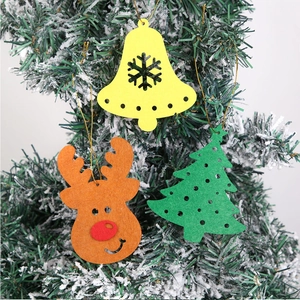 Detailed view of felt reindeer and bell ornaments hanging on a snowy Christmas tree branch