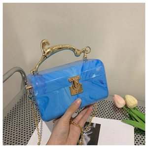 Detail of blue marble acrylic evening bag featuring gold leopard-shaped handle and chain