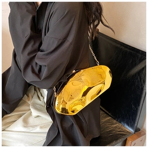 Close-up of golden irregular metal clutch with wave texture and metal chain strap