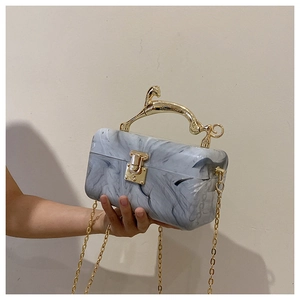 Detail of marble pattern acrylic clutch with golden horse handle and crossbody chain